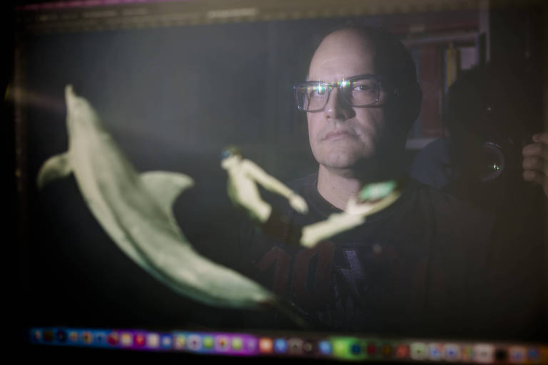 imagem de um homem branco de óculos refletida na tela do computador