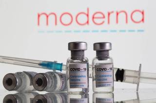Frascos rotulados como de vacinas contra Covid-19 em frente ao logo da Moderna em foto de ilustração