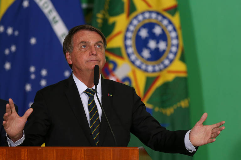 O presidente Jair Bolsonaro, vestido de terno e gravata, abre os braços e olha para o alto durante discurso em evento no Palácio do Planalto