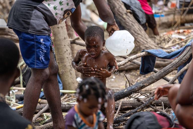 Imigrante haitiano dá banho em seu filho em acampamento improvisado em Del Rio, no Texas
