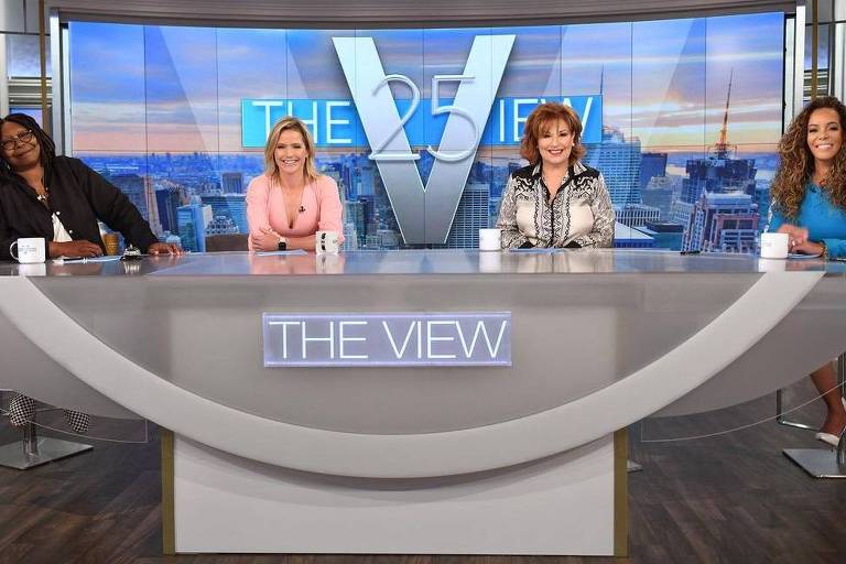 Quatro mulheres sentadas atrás de uma bancada com o escrito 'The View' em azul claro