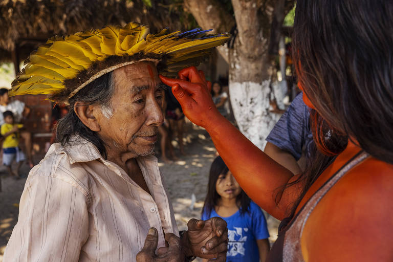 Jovem pinta o rosto do cacique Manoel Kanunxi, 71, antes de uma apresentação cultural do povo manoki