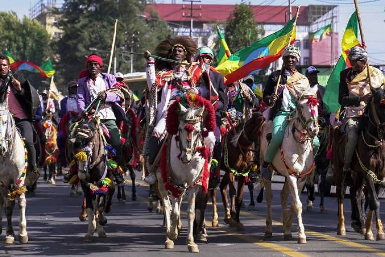 cavalaria desfila segurando bandeiras do país 