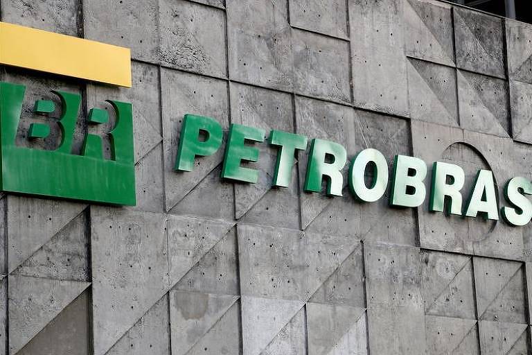 Fotografia mostra logo da Petrobras em verde e amarelo na fachada de um prédio de tijolos cinzas.