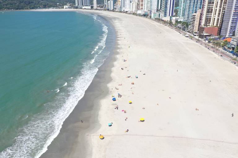 mar azul com uma larga faixa de areia e edifícios altos