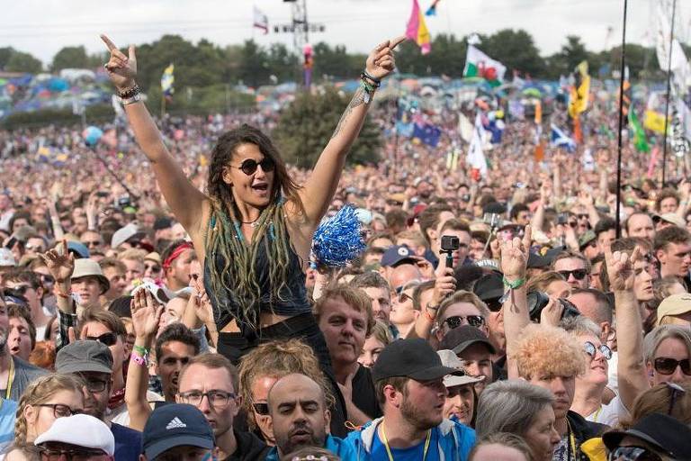 No meio de uma aglomeração de pessoas, uma mulher é erguida e leva os braços para o alto