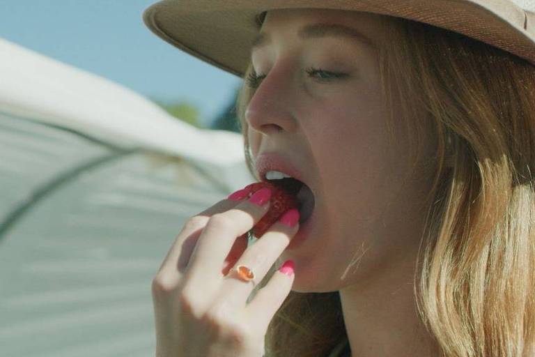 Mulher colocando um morango na boca