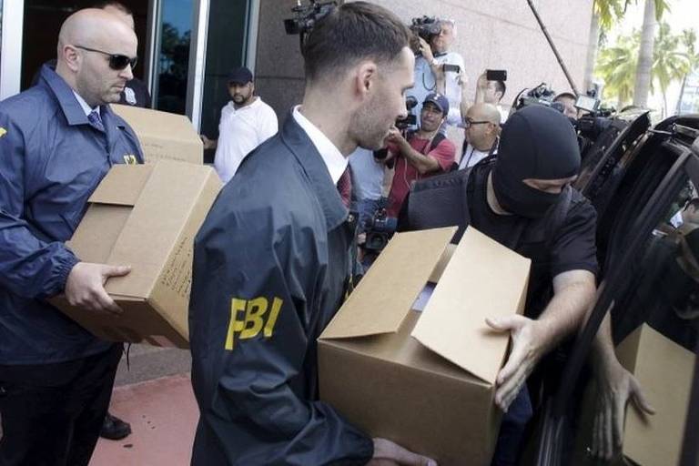 Policiais do FBI carregam caixas até um veículo