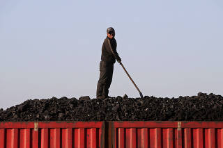 FILE PHOTO - A worker speaks as he loads coal on a truck at a depot near a coal mine from the state-owned Longmay Group on the outskirts of Jixi, Heilongjiang, China
