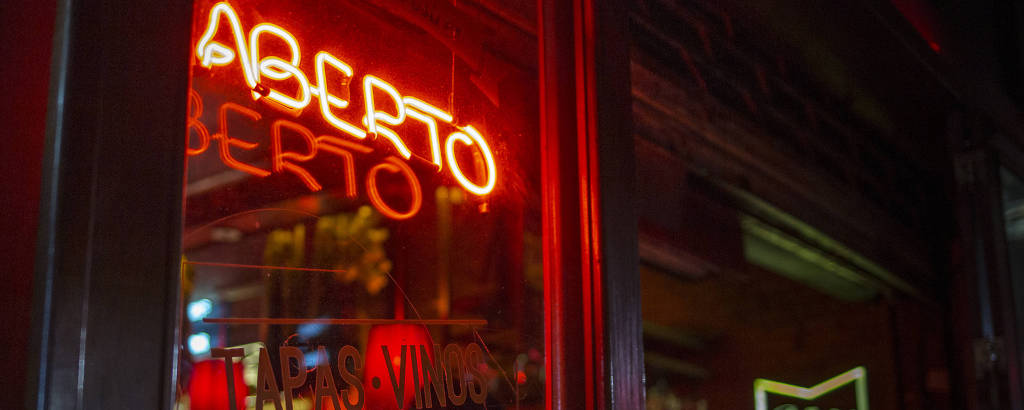 No restaurante espanhol Sancho Bar y Tapas, na rua Augusta, pessoas comem sob a luz neon vermelha 