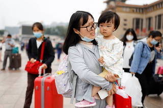 A woman carries a child while walking outside the Beijing Railway Station ahead of China's National Day and the upcoming Golden Week holiday, following the coronavirus disease (COVID-19) outbreak, in Beijing
