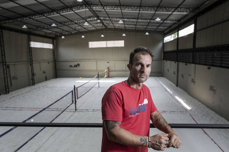 Rodrigo posa para foto com quadra de beach tennis coberta atrás dele