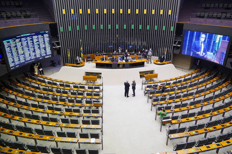Plenário da Câmara dos Deputados praticamente vazio, com deputados no telão