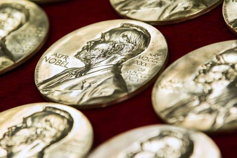 Em uma superficie, há medalhas com o rosto de Alfred Nobel