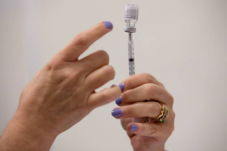 Profissional da saúde segrua uma seringa e ampola de vacina contra a Covid