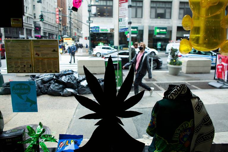 Imagem sombreada de representação de folha de cannabis; ao fundo, iluminada, a rua
