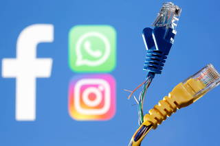 Broken Ethernet cables are seen in front of displayed Facebook, WhatsApp and Instagram logos in this illustration