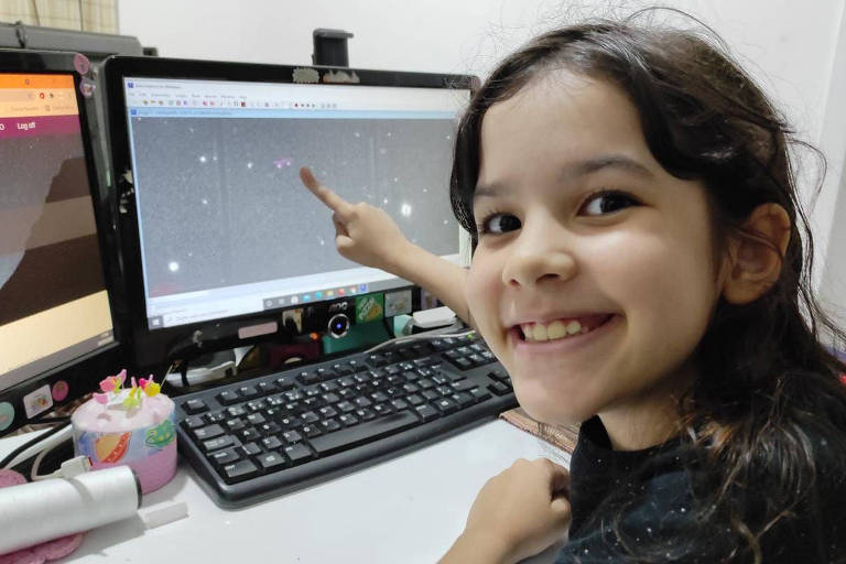 menina aponta para asteróides em tela de computador
