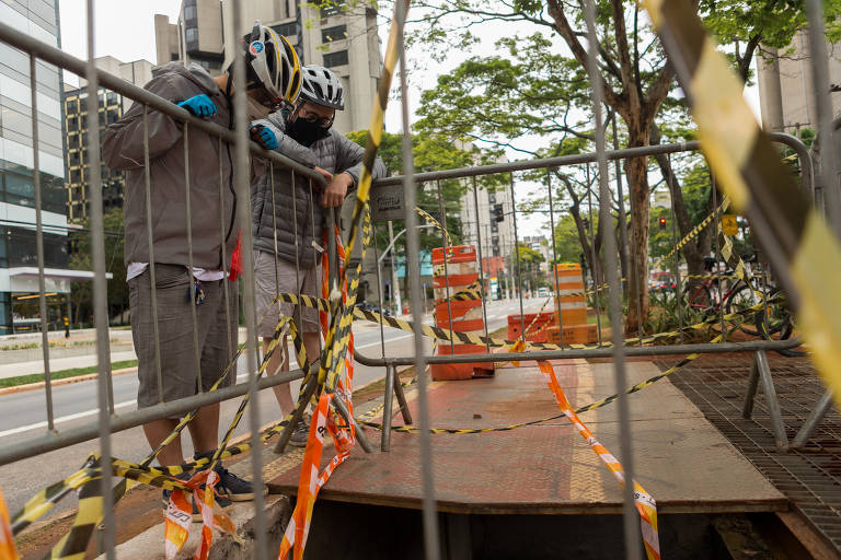 Os ciclistas Thomas Wang, 26 anos, e Felipe Coutinho, 25, observam o buraco na ciclovia da avenida Berrini