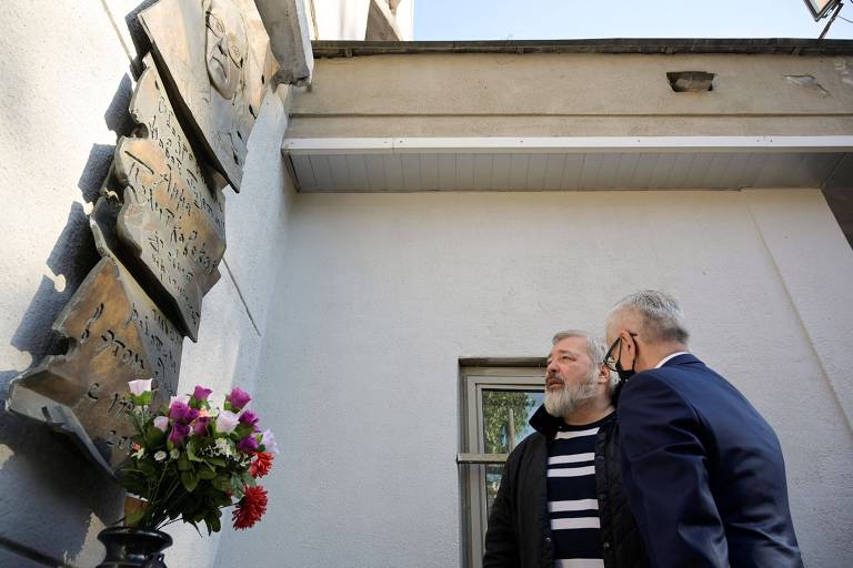 Na véspera de ganhar o Nobel, Muratov (de barba) fala sobre a prescrição da apuração da morte de Anna Politkovskaia junto a monumento à repórter no prédio de seu jornal
