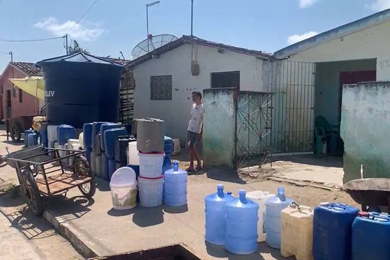 Homem na calçada na cidade de Solânea com vários baldes e caixas d'água