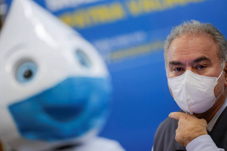 Marcelo Queiroga ao lado do personagam do Zé Gotinha. Ambos usam máscara.