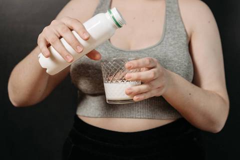 Mulher com garrafa e copo de leite materno nas mãos - Web Stories 
