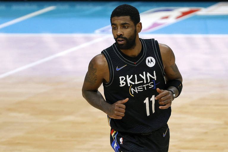 Jogador com uniforme preto corre em quadra com logo da NBA