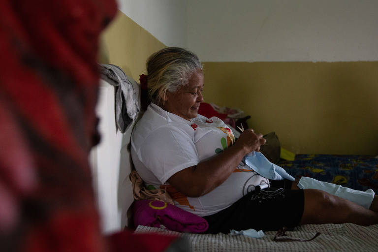 Costureira e cozinheira venezuelana costura roupa para o neto em abrigo para imigrantes em Pacaraima