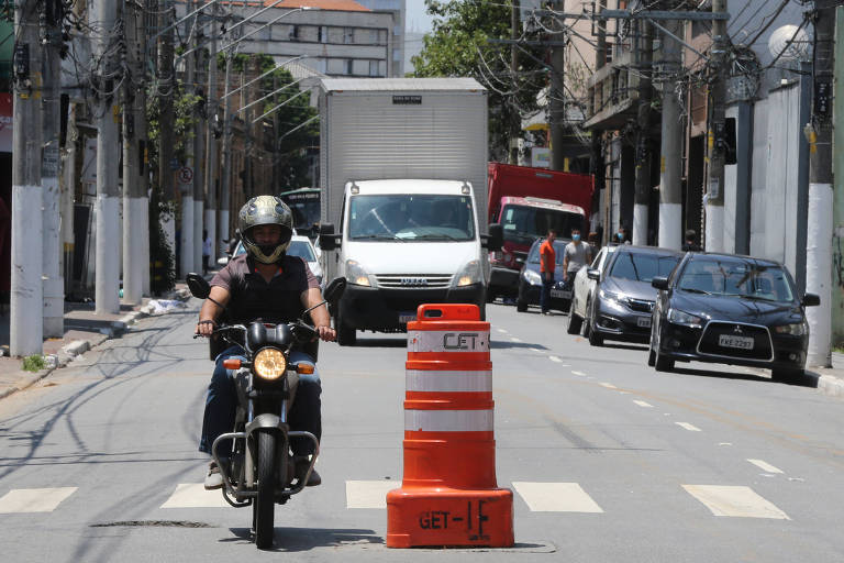 Motociclista passa ao lado de bueiro destampado no cruzamento da rua da Mooca com a rua Mem de Sá, na zona leste