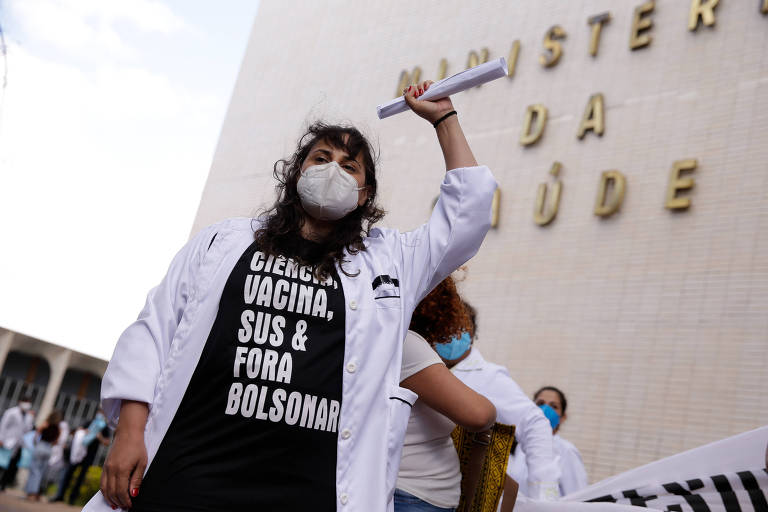 Residente da área da Saúde protesta em frente ao Ministério da Saúde contra o governo de Jair Bolsonaro; em sua camiseta está escrito "Ciência, vacina, SUS e fora, Bolsonaro"