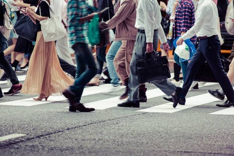 Imagem em close mostra pernas de um grupo de pessoas atravesando uma faixa de pedestre