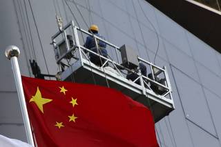 A construction site worker is seen behind China's national flag in Beijing