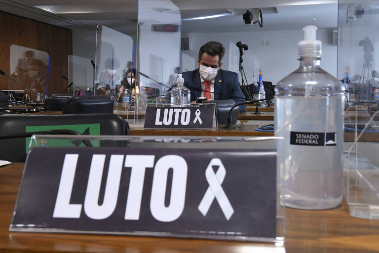 Placas com a inscrição "Luto" em bancada no Senado, com frasco de álcool gel ao lado