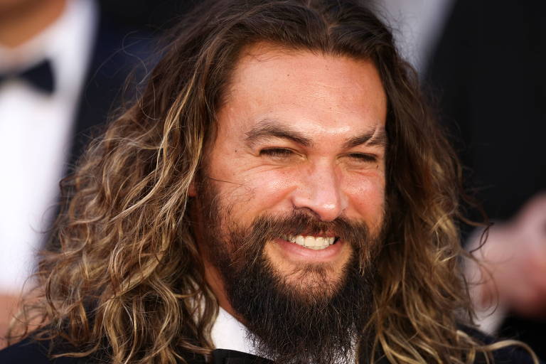 Imagem mostra homem com cabelo grande e barba sorrindo