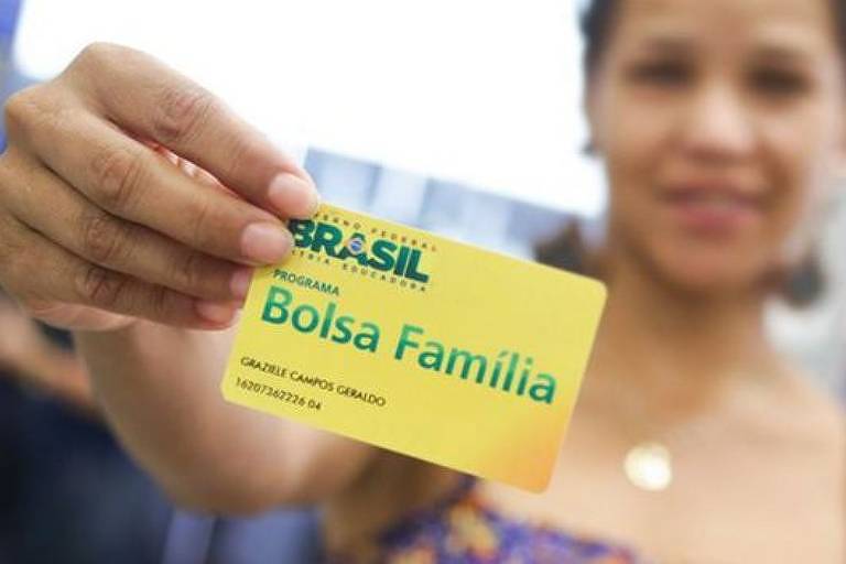Mulher exibe cartão do Bolsa Família