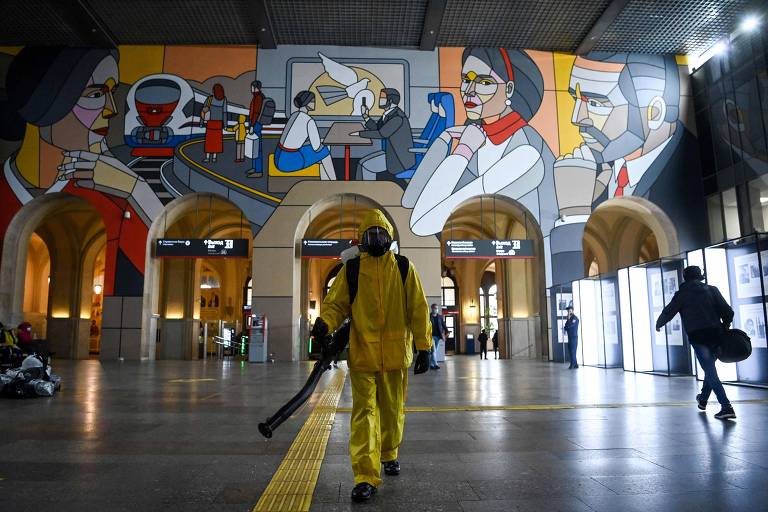 Agente sanitário com equipamento de proteção faz desinfecção em estação de trem em Moscou