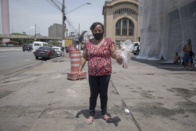 Maria Madalena da Silva segura restos de alimentos que pegou do descarte do Mercadão Municipal