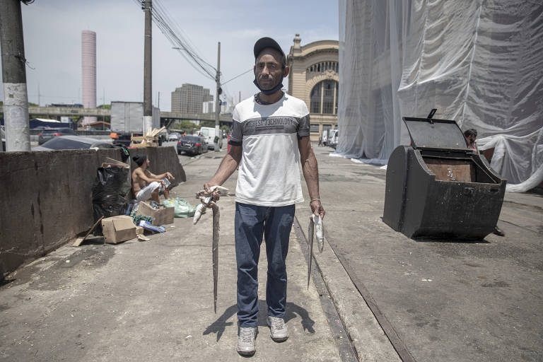 Sivanildo Gomes Ferreira, 58, segura peixes que pegou do descarte de alimentos do Mercadão Municipal, no centro de São Paulo