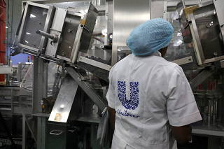 FILE PHOTO: A woman stands behind a machine that is part of a toothpaste manufacturing line at the Unilever factory in Lagos