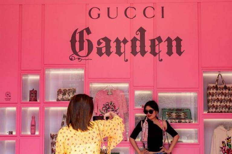 Mulher chinesa posa para foto em frente a uma vitrine da marca Gucci
