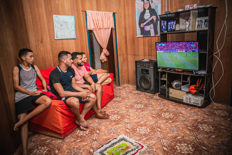 Moradores da Vila Restauração assistindo a um jogo de futebol pela televisão