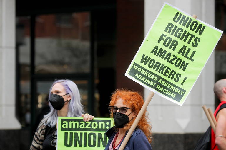 Duas mulheres carregando cartazes com a frase "direitos sindicais para todos os funcionários da Amazon!"