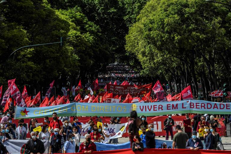Manifestantes carregam bandeiras e cravos vermelhos durante uma manifestação para comemorar o aniversário da Revolução dos Cravos, em Lisboa

