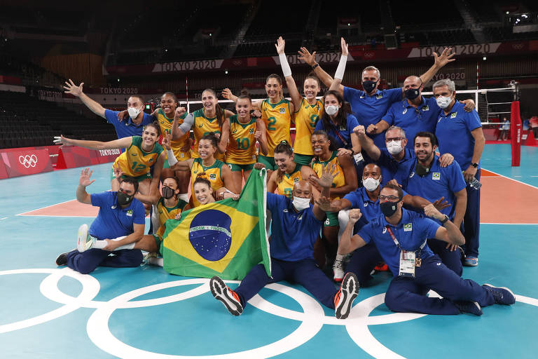 Grupo posa para foto em quadra, com a bandeira do Brasil