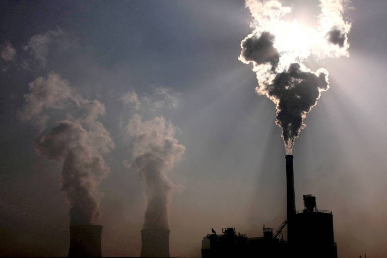 Imagem mostra três chaminés de fábricas emitindo grande volume de fumaça