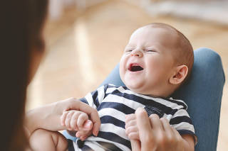 Closeup portrait of laughing newborn baby lying on mother's lap