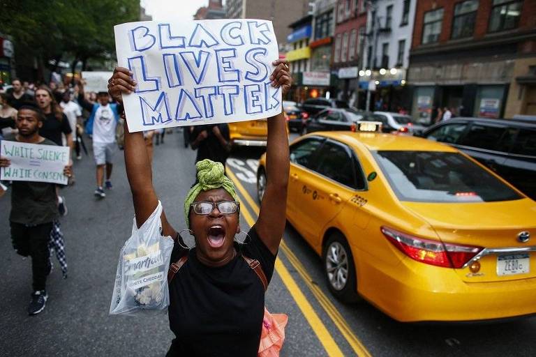Mulher negra ergue cartaz escrito: Black Lives Matter