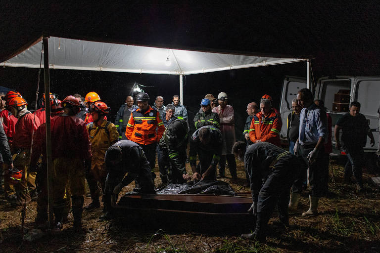 Imagem mostra homens do Corpo de Bombeiros retirando corpo de bombeiro civil morto em soterramento na gruta Duas Bocas, em Altinópolis