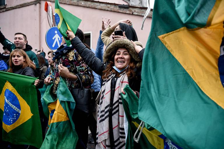 Apoiadores de Bolsonaro seguram bandeiras do Brasil antes da chegada do presidente a Anguillara Vêneta, na Itália